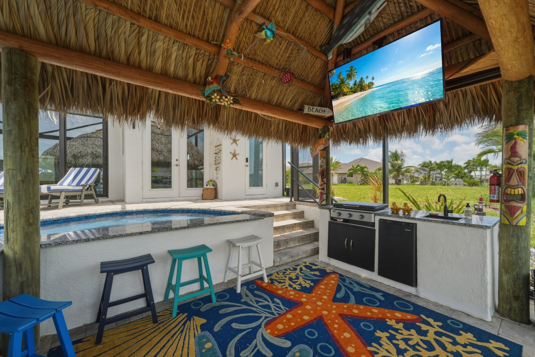 Tiki bar with outdoor kitchen, television, and pool seating