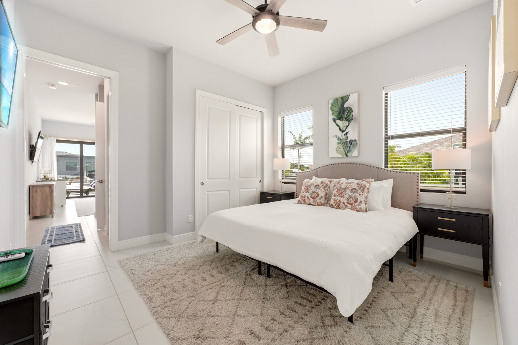 Coastal queen bedroom with windows overlooking the pool area